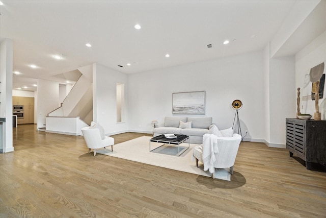 living room featuring recessed lighting, stairway, light wood-style flooring, and baseboards