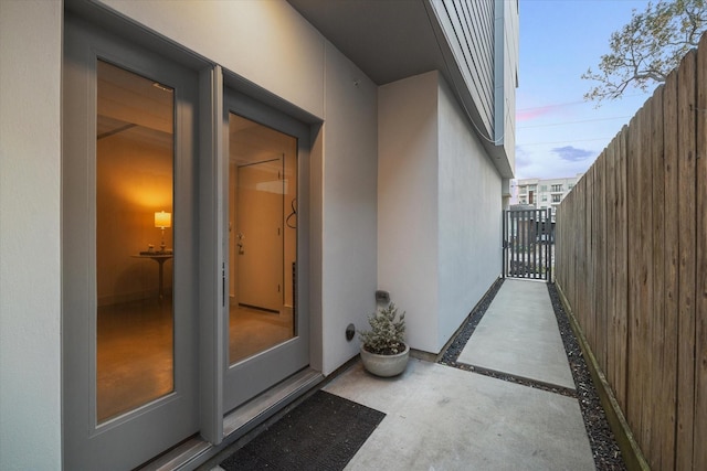 doorway to property featuring stucco siding and fence