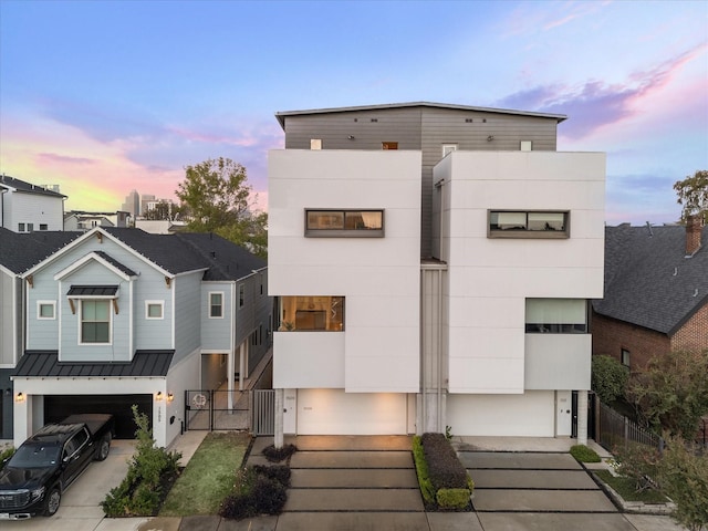 modern home featuring metal roof, a garage, driveway, and a standing seam roof