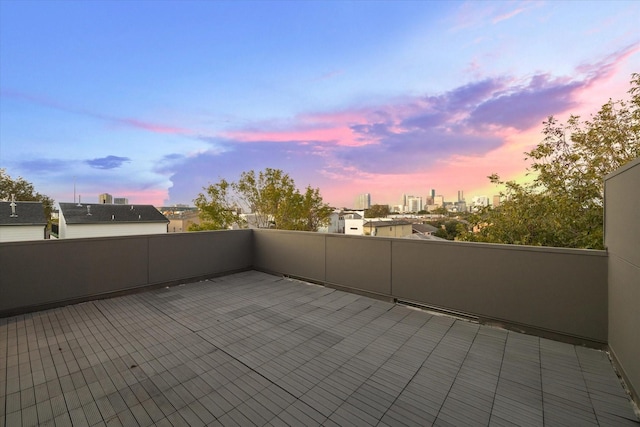 patio terrace at dusk featuring a view of city and a balcony