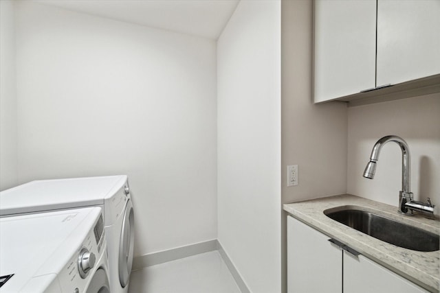 washroom featuring cabinet space, independent washer and dryer, baseboards, and a sink