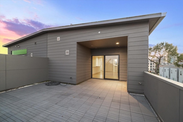 back of house at dusk with a balcony