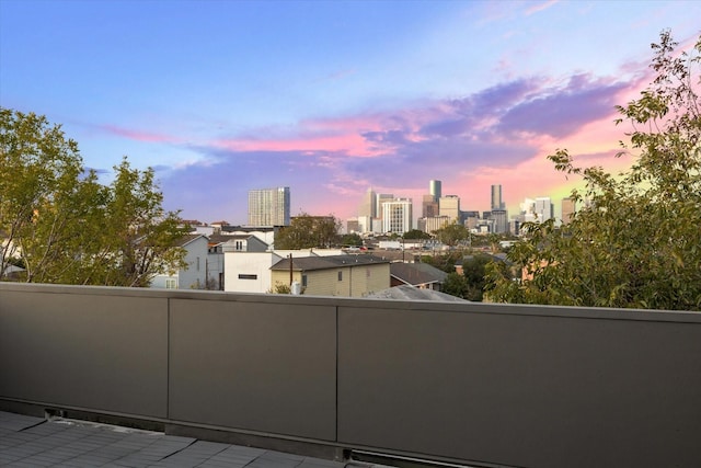 balcony at dusk featuring a city view