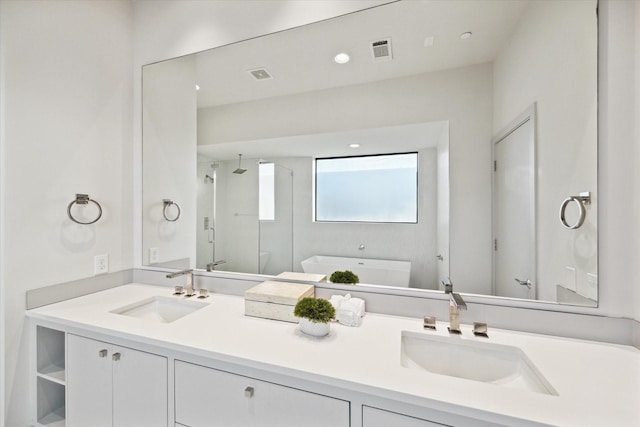 full bath featuring visible vents, a shower stall, a freestanding tub, and a sink