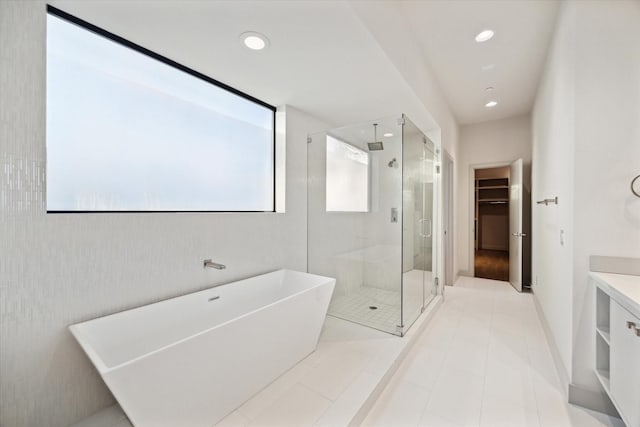 bathroom with a walk in closet, a healthy amount of sunlight, a stall shower, and a freestanding bath