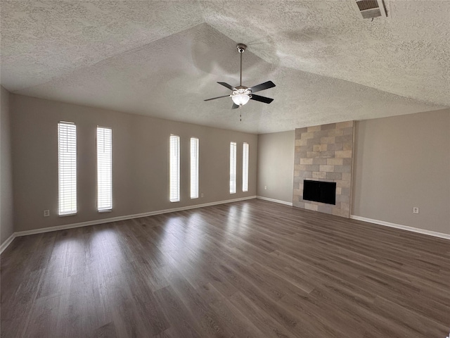 unfurnished living room featuring visible vents, dark wood-type flooring, baseboards, a fireplace, and a ceiling fan