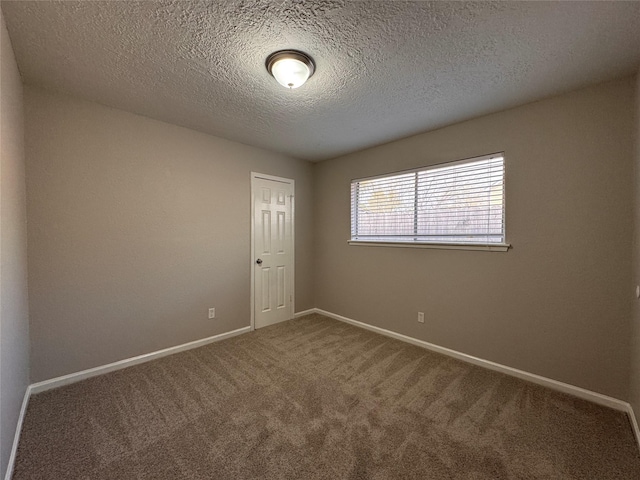 spare room featuring carpet flooring, a textured ceiling, and baseboards