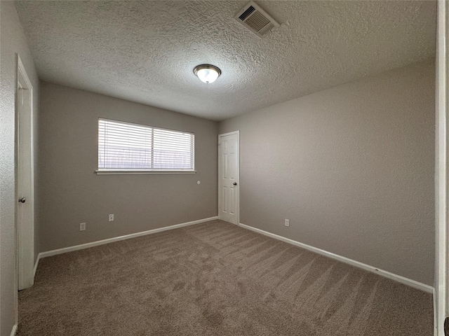 spare room featuring a textured ceiling, carpet, visible vents, and baseboards