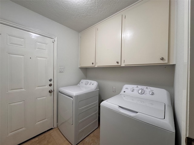 clothes washing area with cabinet space, a textured ceiling, and washing machine and clothes dryer