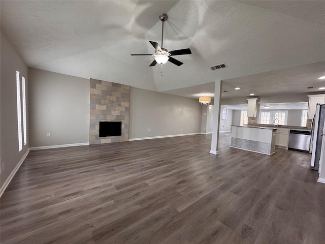 unfurnished living room featuring visible vents, baseboards, dark wood finished floors, vaulted ceiling, and a fireplace