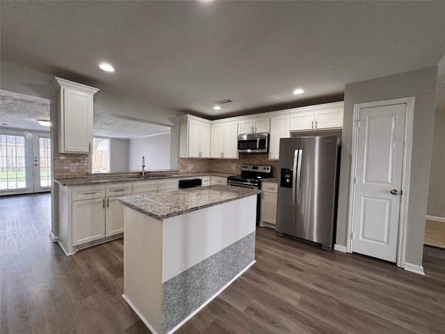 kitchen with white cabinets, appliances with stainless steel finishes, and dark wood-style flooring