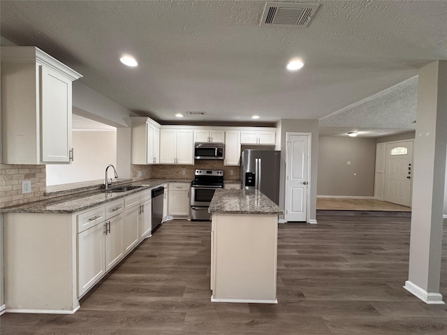 kitchen featuring dark wood-type flooring, visible vents, appliances with stainless steel finishes, and a sink