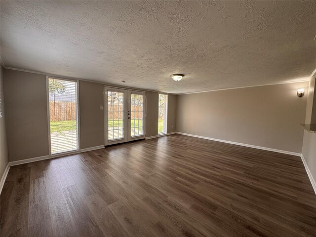 empty room with a textured ceiling, dark wood-type flooring, baseboards, and ornamental molding