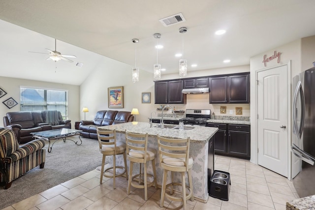 kitchen featuring visible vents, under cabinet range hood, a sink, open floor plan, and stainless steel appliances