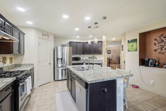 kitchen with light stone counters, appliances with stainless steel finishes, an island with sink, and a sink