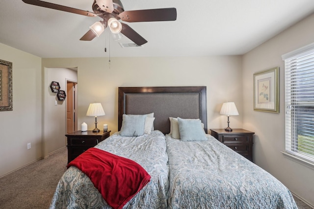 carpeted bedroom featuring visible vents, multiple windows, and a ceiling fan