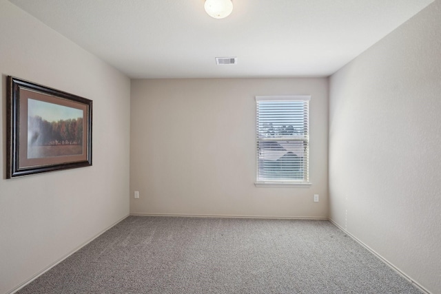 carpeted empty room featuring baseboards and visible vents