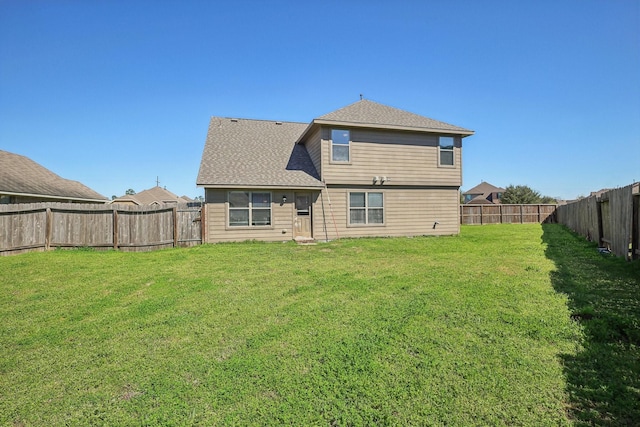 rear view of property with a lawn, roof with shingles, and a fenced backyard