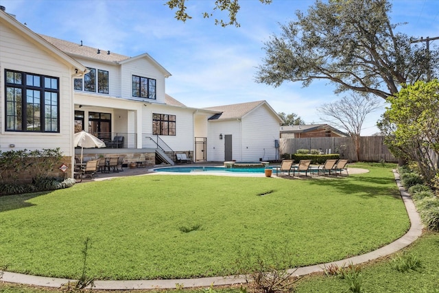 back of house with a patio, fence, a yard, roof with shingles, and a fenced in pool