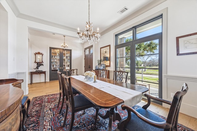 dining room with visible vents, wainscoting, light wood finished floors, and a chandelier