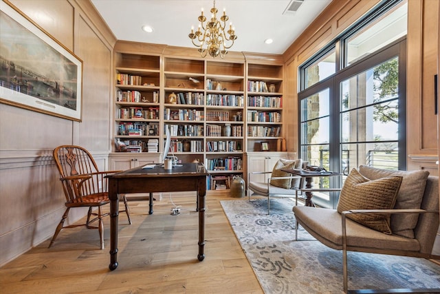 living area featuring built in features, visible vents, a notable chandelier, and wood finished floors