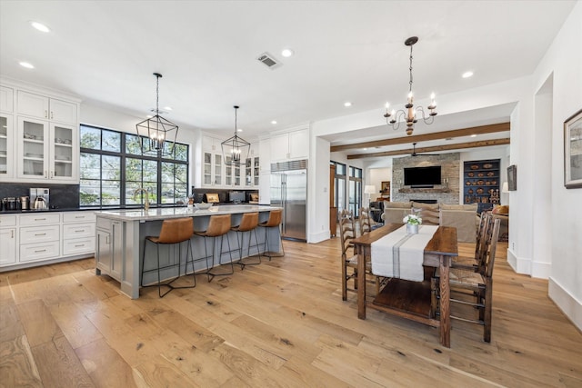 kitchen featuring white cabinets, light wood-type flooring, a chandelier, and stainless steel built in fridge