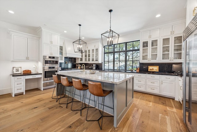 kitchen with white cabinetry, light wood-style flooring, and stainless steel double oven