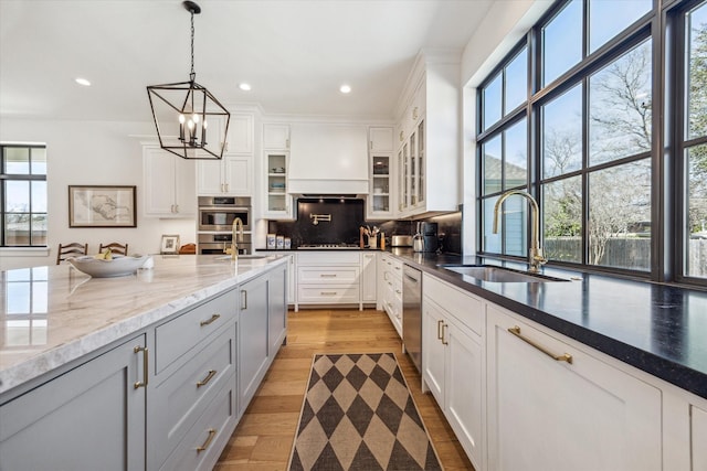 kitchen with glass insert cabinets, premium range hood, backsplash, and a sink