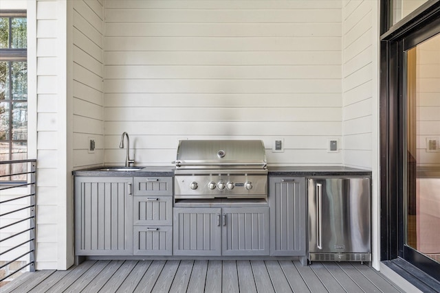 wooden deck with a sink, an outdoor kitchen, and grilling area