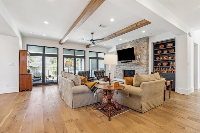 living area featuring visible vents, beam ceiling, light wood-style flooring, and a fireplace