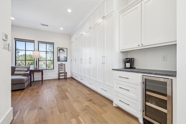 interior space featuring beverage cooler, visible vents, light wood finished floors, recessed lighting, and a dry bar