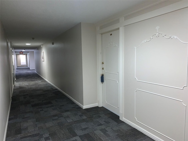 corridor with baseboards and dark carpet