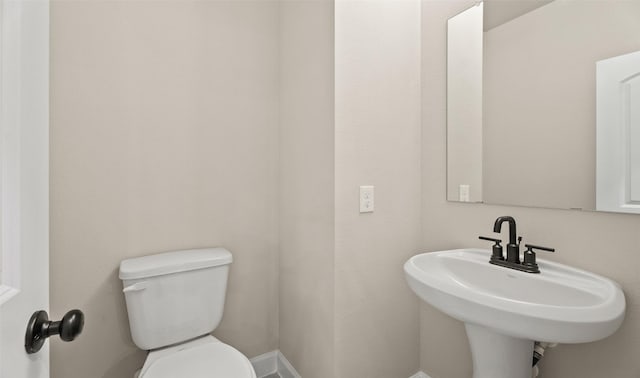 bathroom with toilet, baseboards, and a sink