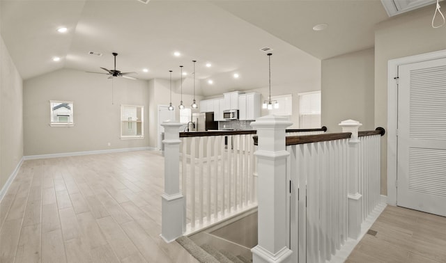 kitchen featuring a ceiling fan, white cabinetry, stainless steel appliances, light wood-style floors, and lofted ceiling