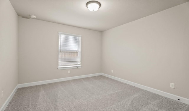 carpeted empty room featuring baseboards