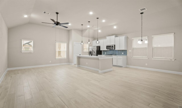 13109 Mundet Dr, Houston, TX 77047 - kitchen with open floor plan, vaulted ceiling, stainless steel appliances, a kitchen island with sink, and a ceiling fan