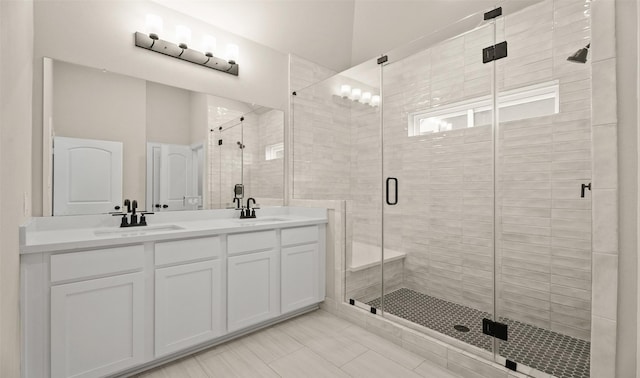 bathroom featuring a sink, a stall shower, and double vanity