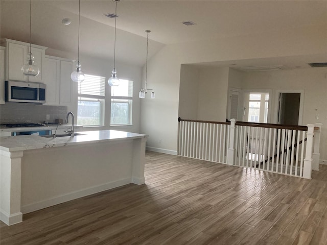 13109 Mundet Dr, Houston, TX 77047 - kitchen with stainless steel microwave, wood finished floors, tasteful backsplash, plenty of natural light, and lofted ceiling