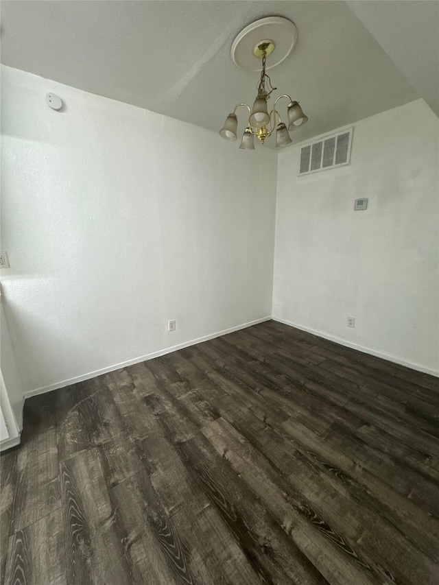 empty room with visible vents, baseboards, an inviting chandelier, and dark wood-style flooring