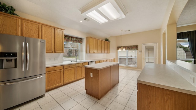 kitchen with stainless steel refrigerator with ice dispenser, a kitchen island, light countertops, light tile patterned floors, and decorative backsplash