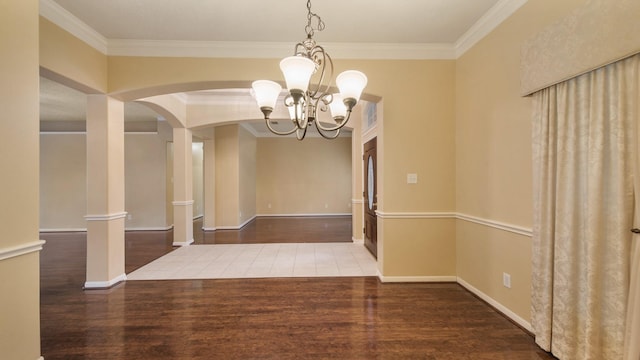 unfurnished dining area featuring baseboards, arched walkways, wood finished floors, and ornamental molding