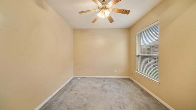 carpeted spare room featuring baseboards and ceiling fan