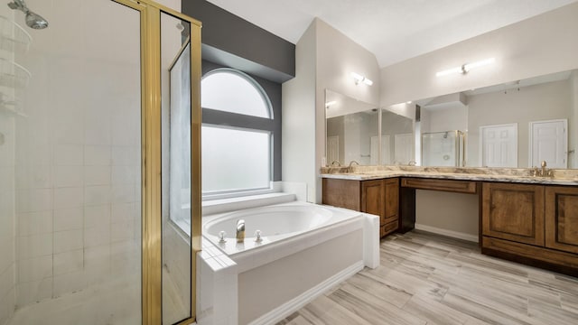 bathroom featuring double vanity, a garden tub, a stall shower, and a sink