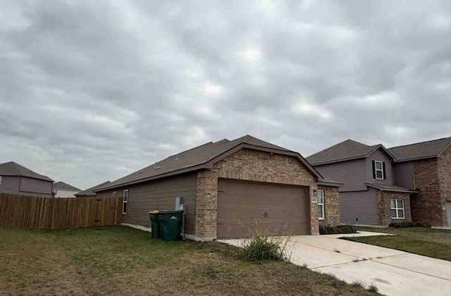 view of side of home featuring a garage, a yard, driveway, and fence