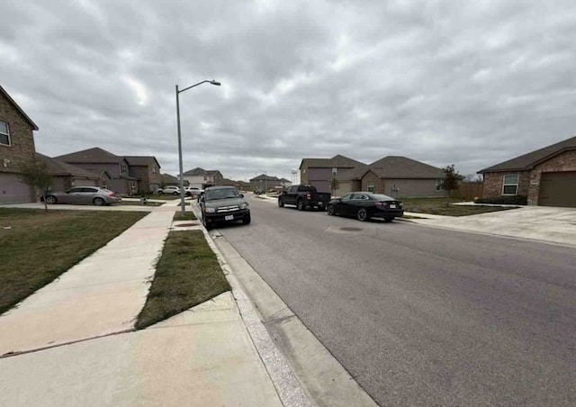 view of road with a residential view, curbs, sidewalks, and street lighting