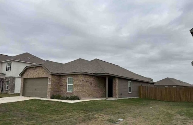 ranch-style home featuring a front lawn, fence, concrete driveway, a garage, and brick siding