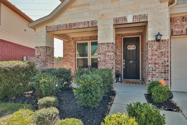 property entrance featuring a garage, brick siding, and stone siding