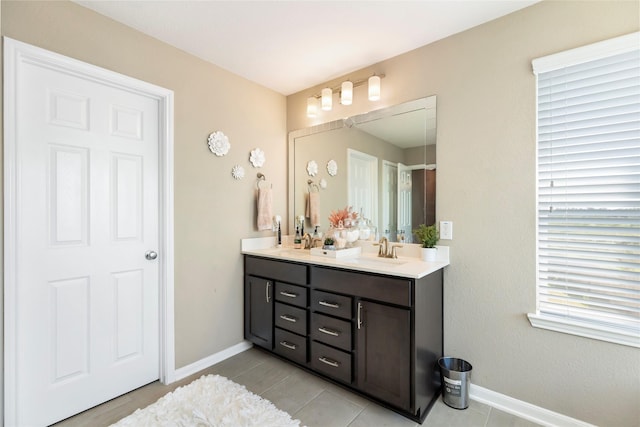 bathroom featuring double vanity, baseboards, tile patterned floors, and a sink