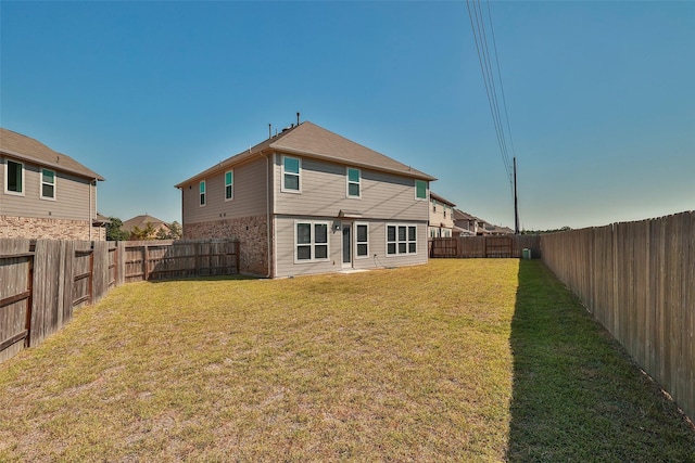 back of property featuring a fenced backyard and a yard