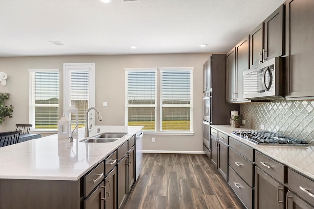 kitchen featuring dark brown cabinetry, dark wood finished floors, light countertops, stainless steel appliances, and a sink